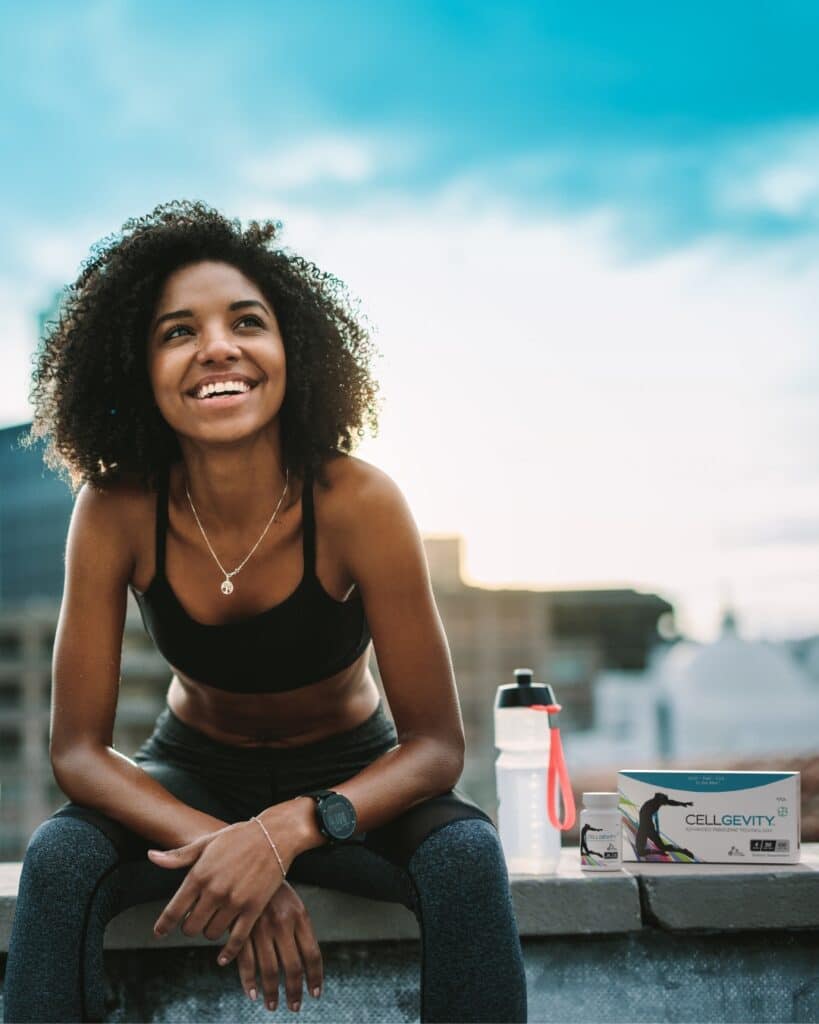 Image of a fit young lady sitting next to a box of Cellgevity